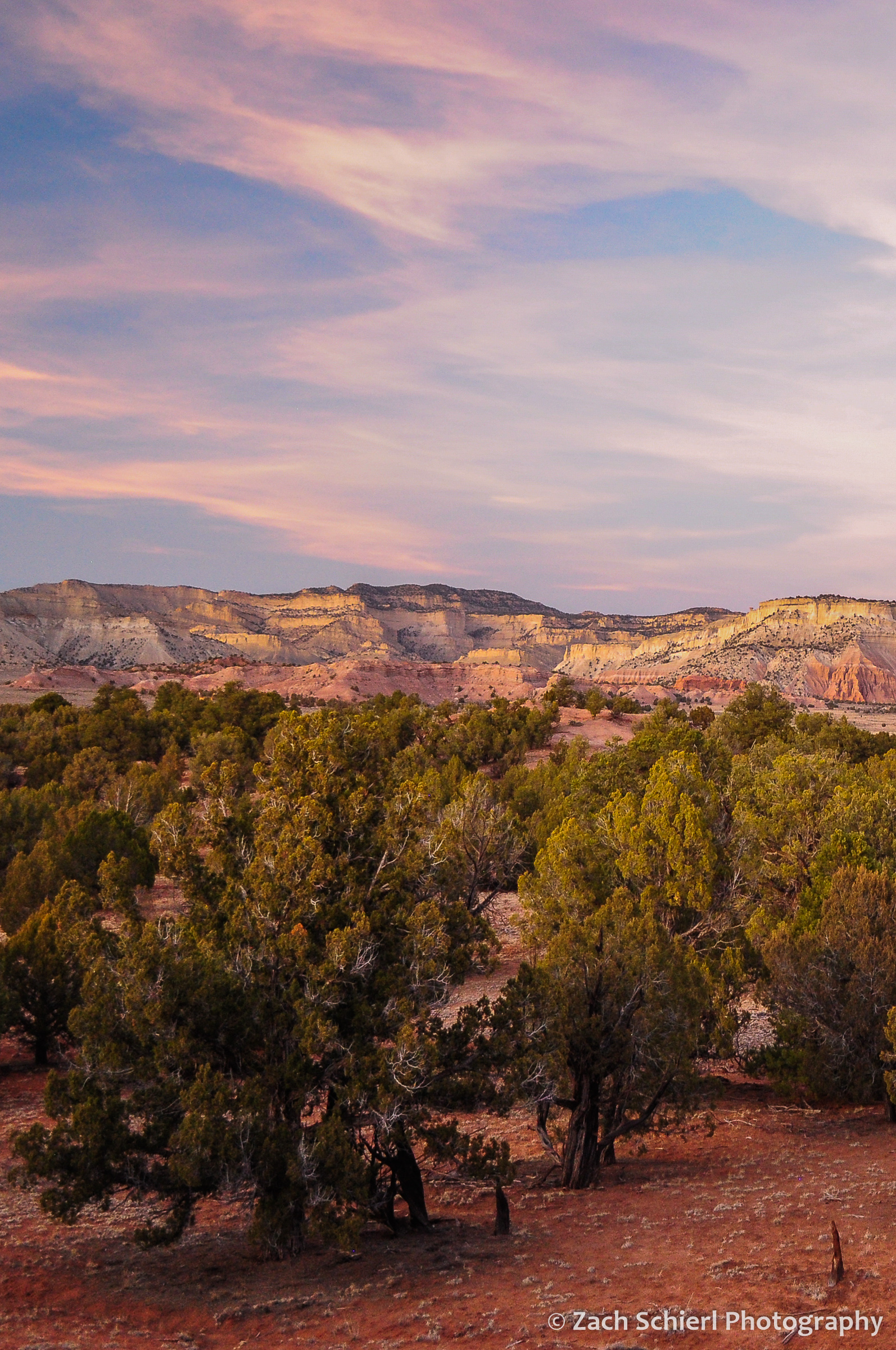 Pink clouds and a band of pink rocky cliffs at sunset