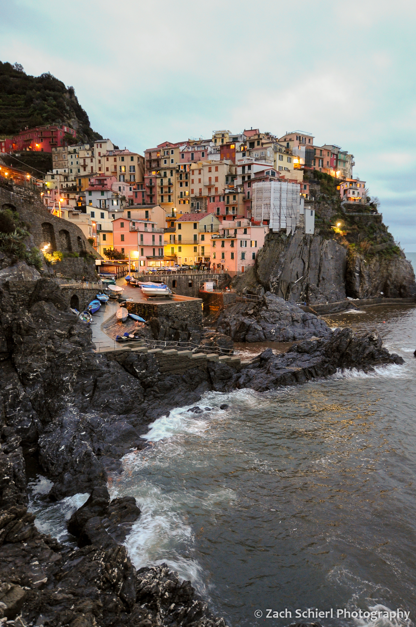 Colorful buildings of Manarola line the waterfront at dusk.