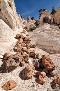 Pink and brown boulders lie strewn in a chute of white tuff