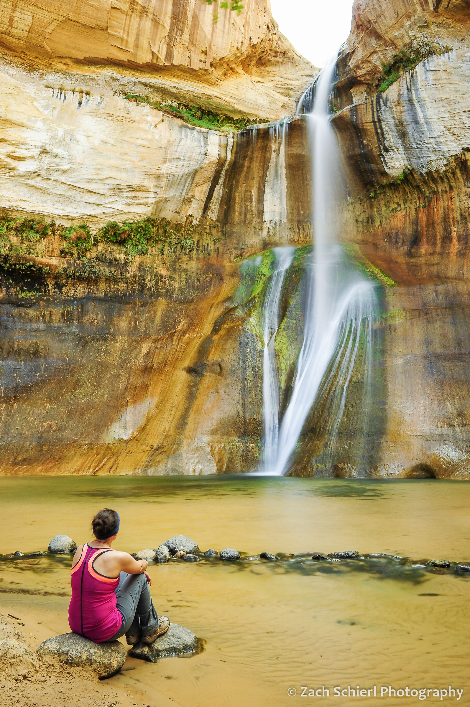 Sitting on a rock looking at a waterfalls tumbling from the sandstone cliffs.
