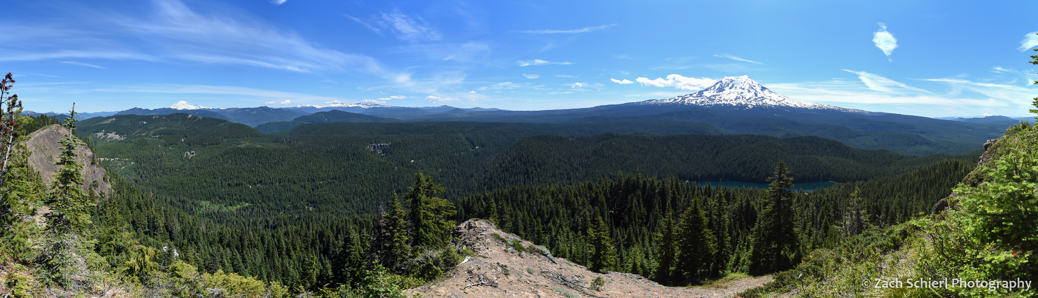 Panorama of forested landscape dotted by tall volcanic peaks.