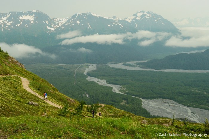 A deep mountain valley with a braided stream and some clouds