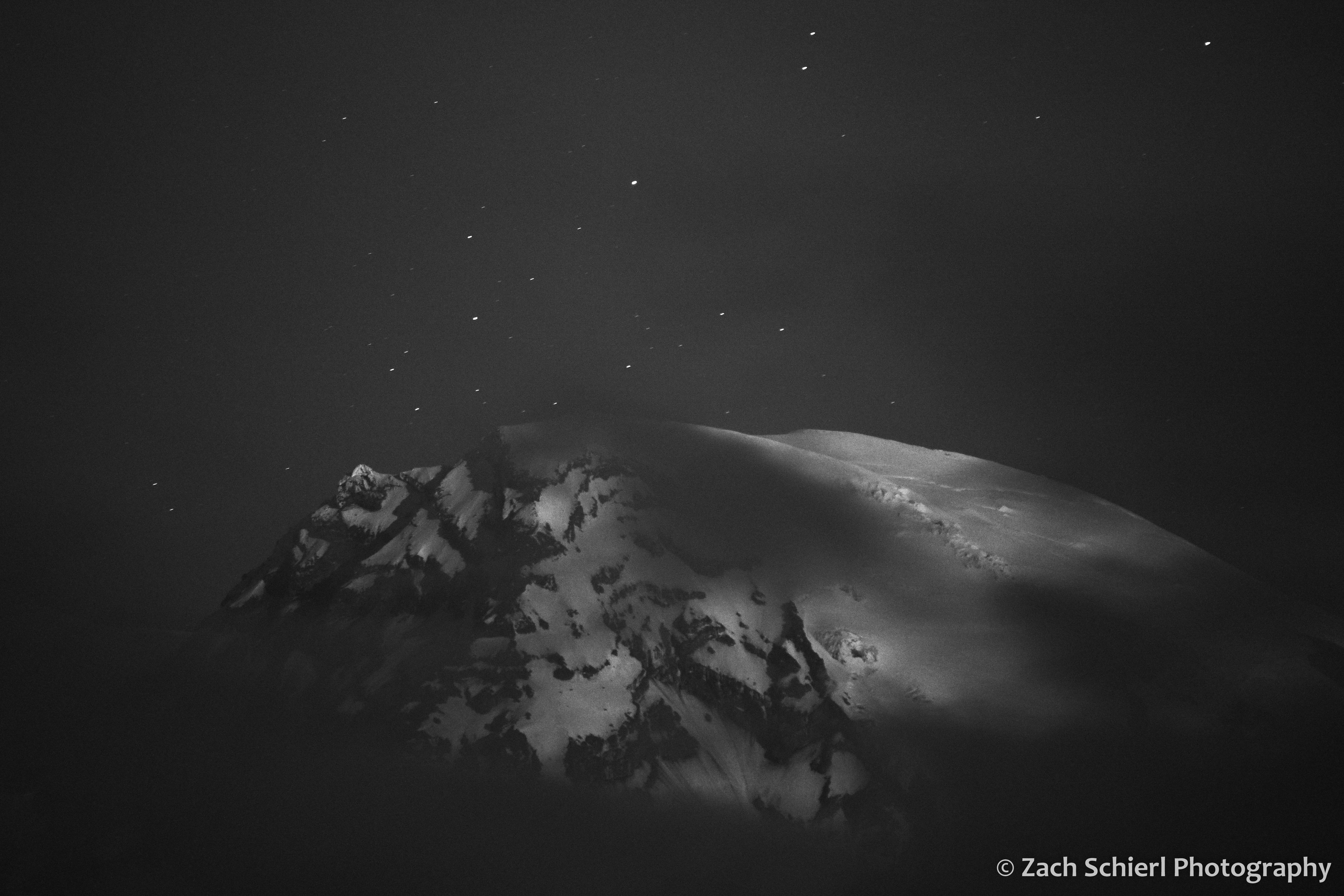White icefields and glaciers at the summit of a peak are visible through some clouds