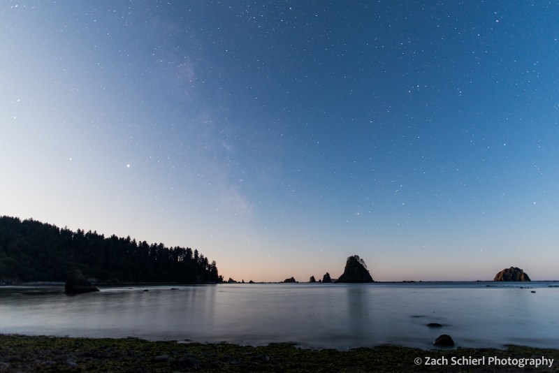 The Milky Way is just barely visible in the sky over the coastline