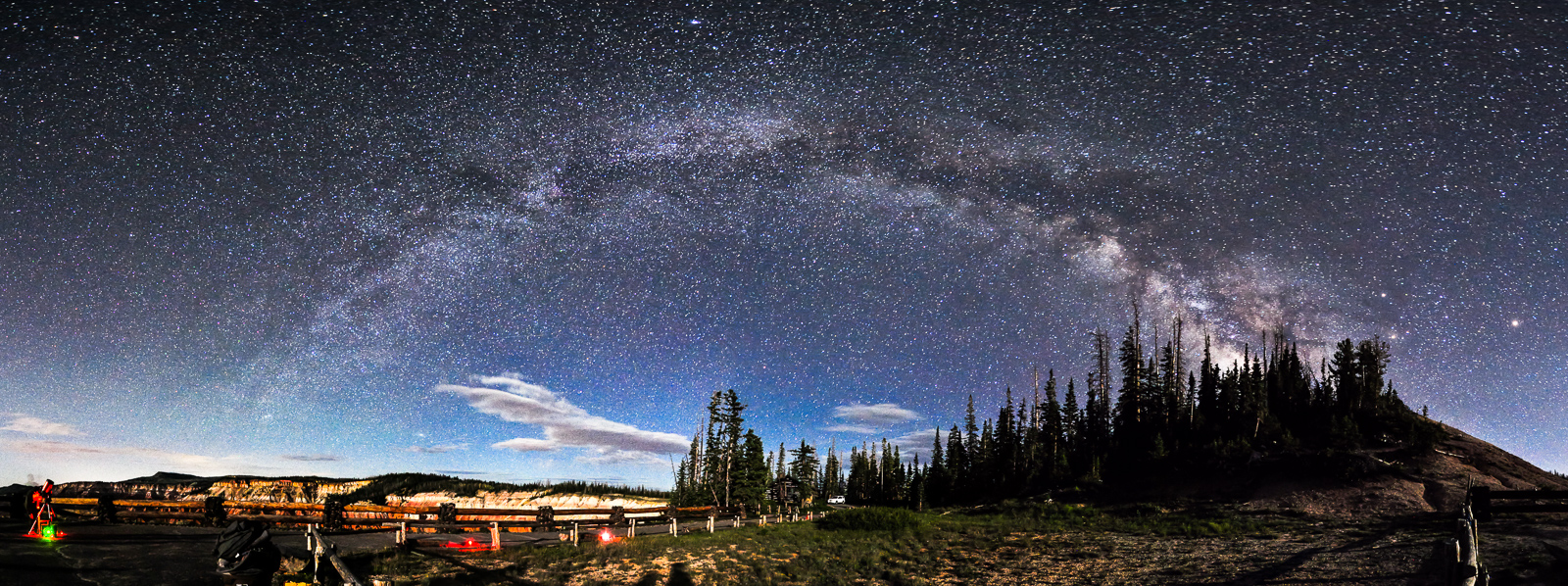 The Milky Way stretches from horizon to horizon with some clouds hovering near the horizon.