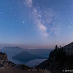 The Milky Way is visible in the night sky over a smoke filled lake.