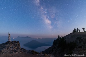 The Milky Way is visible in the night sky over a smoke filled lake.