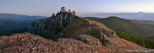 A rocky ridge with a lookout tower on top is seen as the sky darkens to twilight in the background