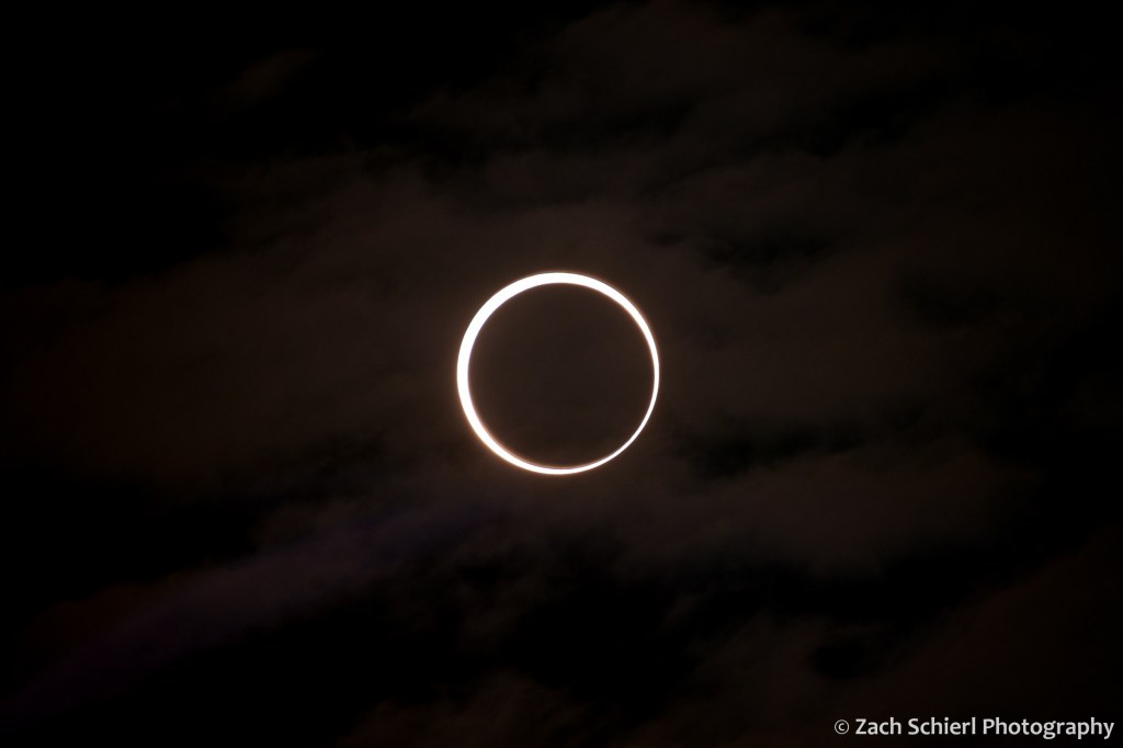 A bright ring of sunlight surrounds the dark moon